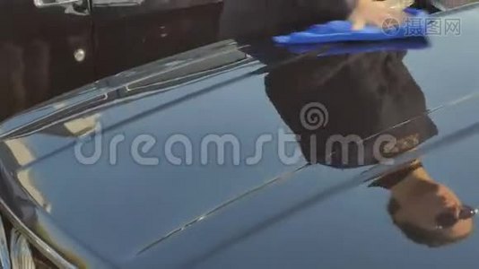 戴墨镜的漂亮卷发女孩清洁了一辆老式汽车的引擎盖视频