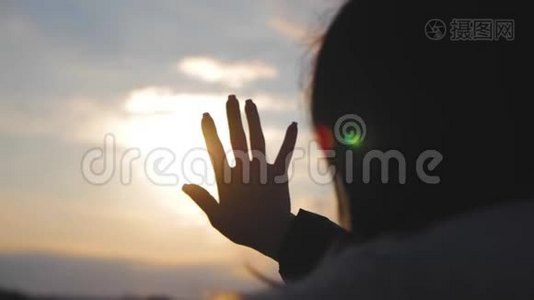 女孩在日落时用手看太阳。视频