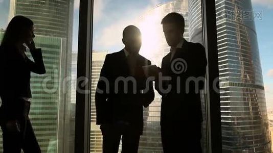 两个多文化的商人站在办公室的窗口边说话握手视频