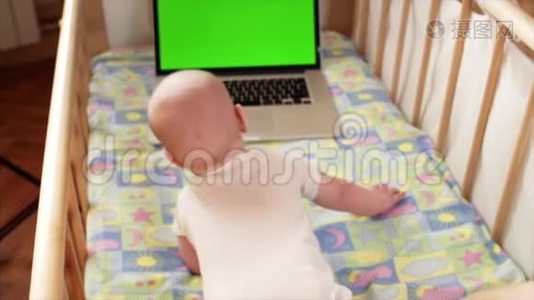 可爱的小男孩在笔记本电脑上用彩色屏幕快速旋转视频