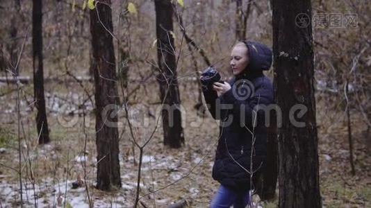 女孩摄影师走在秋天的森林里，拍摄大自然的照片。 电影镜头，慢动作。 第一场雪视频