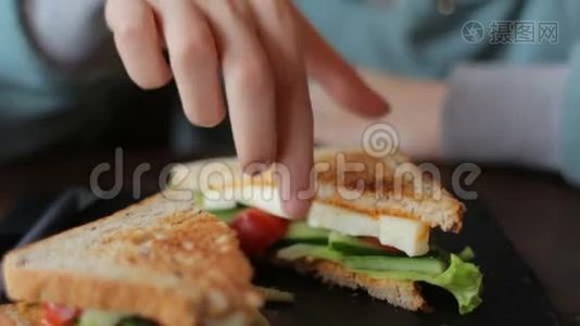 靠近女人的手在咖啡馆里吃美味的三明治和新鲜蔬菜奶酪视频