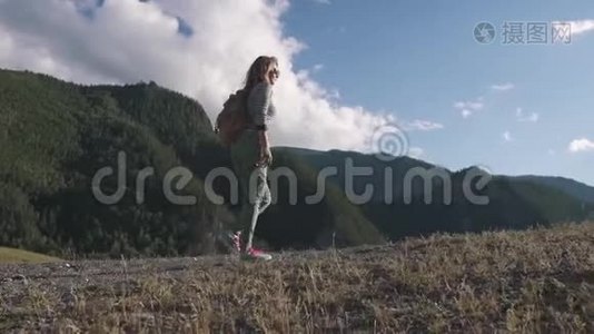 山云背景下的少女旅人.. 一个带背包的游客上坡。视频