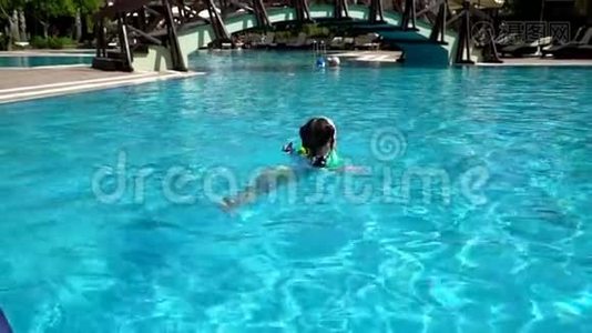 小女孩在游泳池里游泳。 在水里旋转。视频