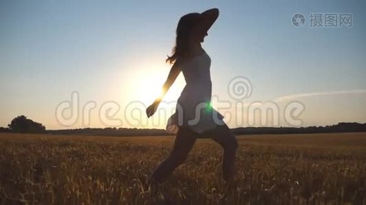 日落时，小女孩正沿着蓝天下的麦田奔跑。 女人正在草地上慢跑。 太阳照耀着视频