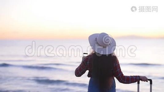 年轻的女游客在海边为日落或黎明拍照视频