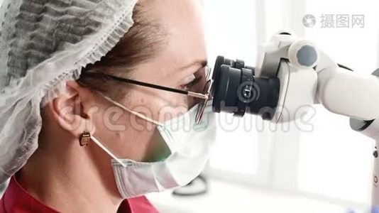 一位戴眼镜的妇女，带着一位专业的牙医，在她的口腔显微镜下工作视频