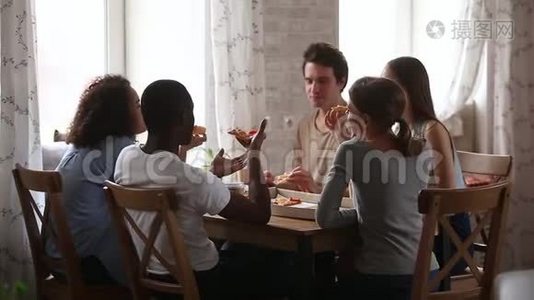 快乐的多种族的年轻朋友谈论吃比萨饼分享咖啡馆视频