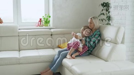 母亲在后台测量生病孩子的体温。 病儿高烧躺在家里的沙发上视频