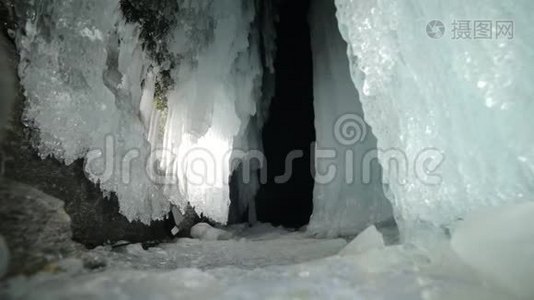 在贝加尔湖冰洞旅行的人。 去冬岛旅行。 背包客正在冰窟散步。 旅行者看着视频