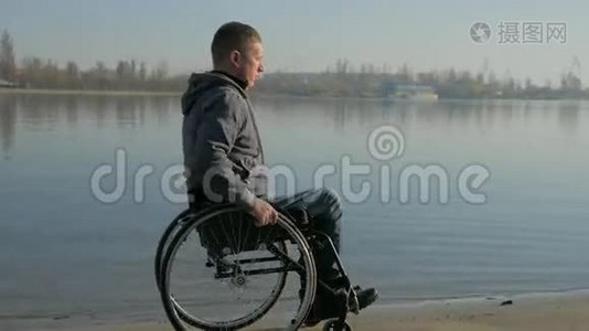 轮椅上的残疾人骑着沙子，坐着轮椅在河边，视频