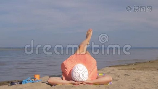 美丽的女人躺在海滩上做热身腿。视频