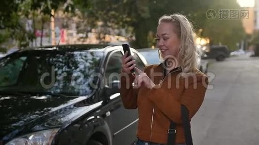 年轻快乐的女人在街上的智能手机上拍新照片。 在路上为社交网络做自拍的女孩视频