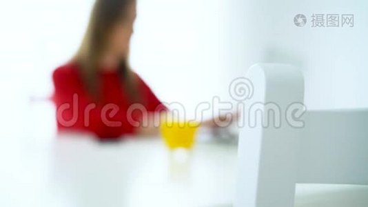 微笑的女人坐在白色的家庭办公室，用笔记本电脑工作视频