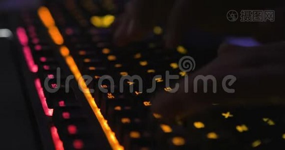 在背景模糊的黑暗环境下，双手打字多色LED键盘视频