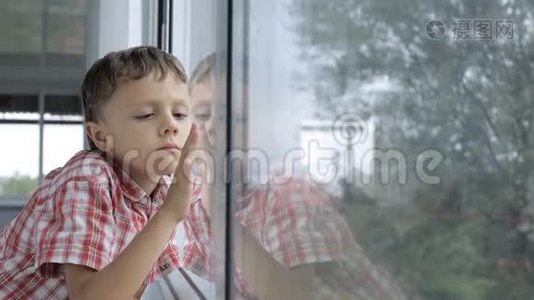 伤心的小男孩白天站在家窗户附近视频