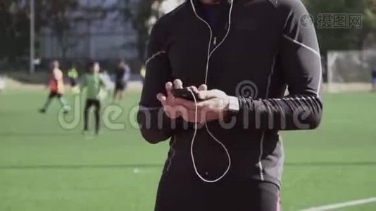主题体育与健康.. 一个年轻的白人男子使用智能手机smarfton听耳机音乐。 技术视频