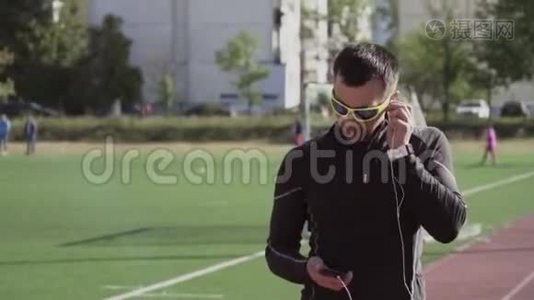 主题体育与健康.. 一个年轻的白人男子使用智能手机smarfton听耳机音乐。 技术视频