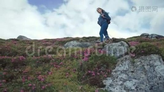 小角度拍摄一位年轻的旅游妇女背着背包走下花山欣赏风景视频