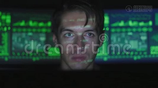 黑客程序员在计算机上工作，而绿色代码字符在网络安全中心反射他的脸视频