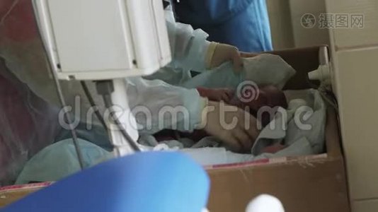 护士戴手套，浴衣用尿布覆盖新生儿在妇产医院哭泣的婴儿。 新生儿视频