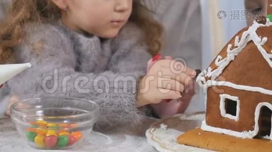 小孩子用五颜六色的糖果装饰姜饼屋视频