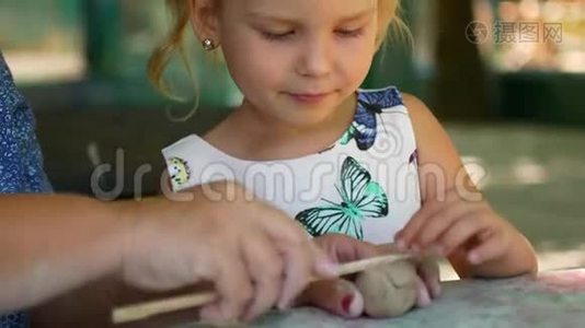 一个小女孩在祖母的帮助下雕刻泥塑视频