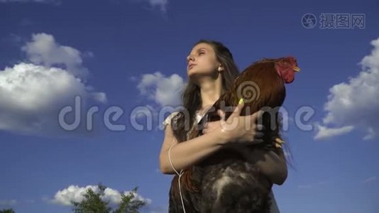布鲁内特手里拿着公鸡，背景是云彩，乡村生活视频