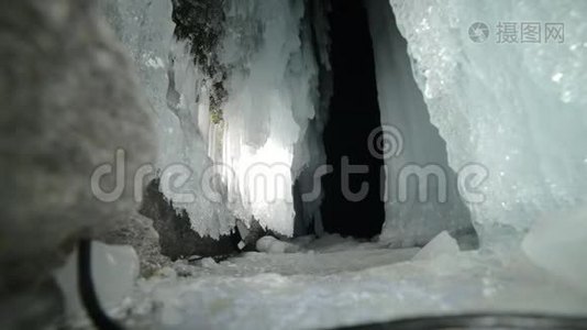 在贝加尔湖冰洞旅行的人。 去冬岛旅行。 背包客正在冰窟散步。 旅行者看着视频