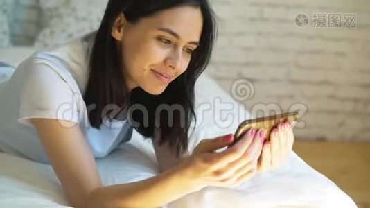 年轻女子躺在床上，用智能手机视频聊天视频