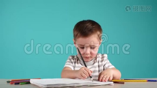 快乐的孩子用铅笔在相册里画画，孤立在蓝色上。视频