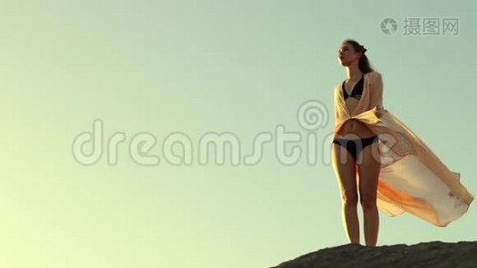 女孩在日落时呆在海滩上，看着水平视频