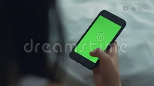 女人用绿色屏幕触摸智能手机。 女人手拿手机视频