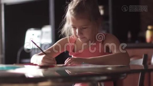 六岁的孩子坐在一张桌子旁画房子。 清晨阳光下的小女孩视频