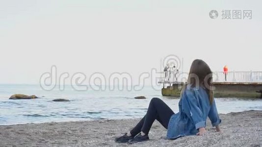 慢动作体贴的女人看海景，听冲浪，在温暖的夜晚坐在沙滩上。视频