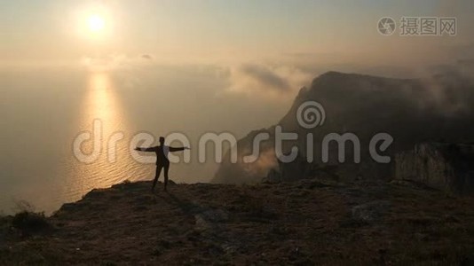 西尔休特年轻女子张开双臂，从克里米亚的一座高山上观察海上美丽而壮观的日落视频