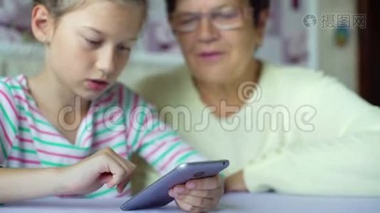 年轻可爱的孙女教祖母如何在家里使用智能手机视频