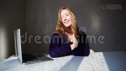 迷人的女孩坐在笔记本电脑附近微笑，等待来自英国的电子邮件。视频