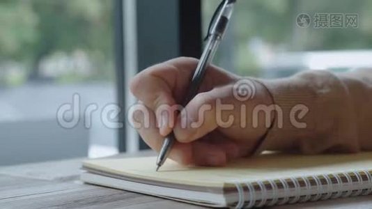 穿浅色毛衣的人用黑色钢笔在笔记本上写字，特写..视频