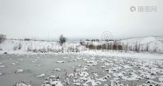 冰雪覆盖的池塘和白雪覆盖的植物。 冬季景观。视频