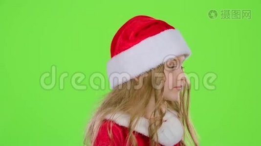 戴着红色圣诞帽的小女孩送空气亲吻。 绿色屏幕。 慢动作视频