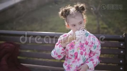 可爱的蹒跚学步的女孩在城市公园吃冰淇淋。视频