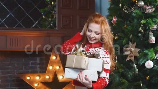 可爱的红头发女孩穿着红色毛衣靠近圣诞树手里拿着礼物。视频