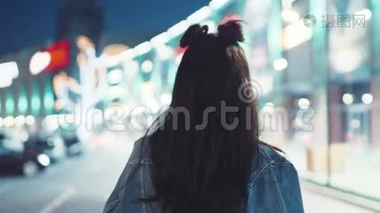 年轻的黑发女孩穿着牛仔裤夹克和时髦的发型，红唇在夜城里徘徊，转向视频