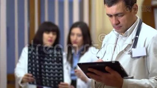 一位男医生手里拿着一块药片。 在背景中，医生检查x光..视频