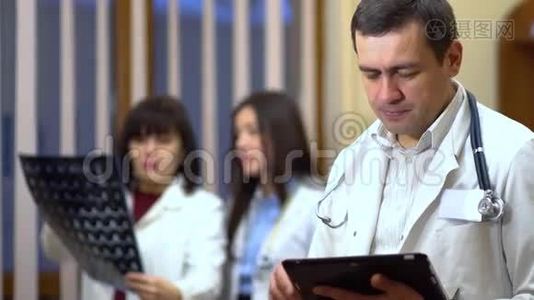 一位男医生自信地看着相机。 在背景中，医生正在检查X光。视频