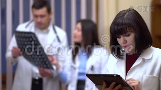 一位女医生自信地看着相机。 在背景中，医生正在检查X光。视频