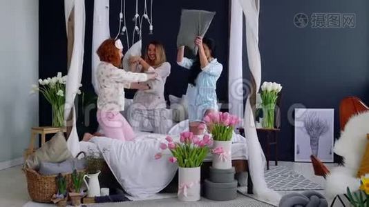 为了庆祝婚礼，三个年轻的女人在一个睡衣派对上打枕头。 美丽的女人笑着视频