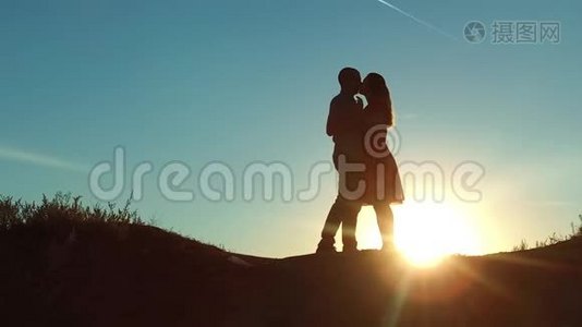 情侣在夕阳下剪影亲吻拥抱.. 慢动作视频。 年轻夫妇在日落时接吻。 男人和女孩见面视频
