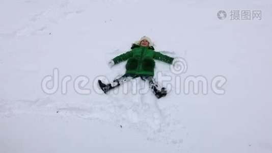 女孩做雪天使。 女孩展示雪天使。 雪天使-在雪地里玩耍的女孩视频